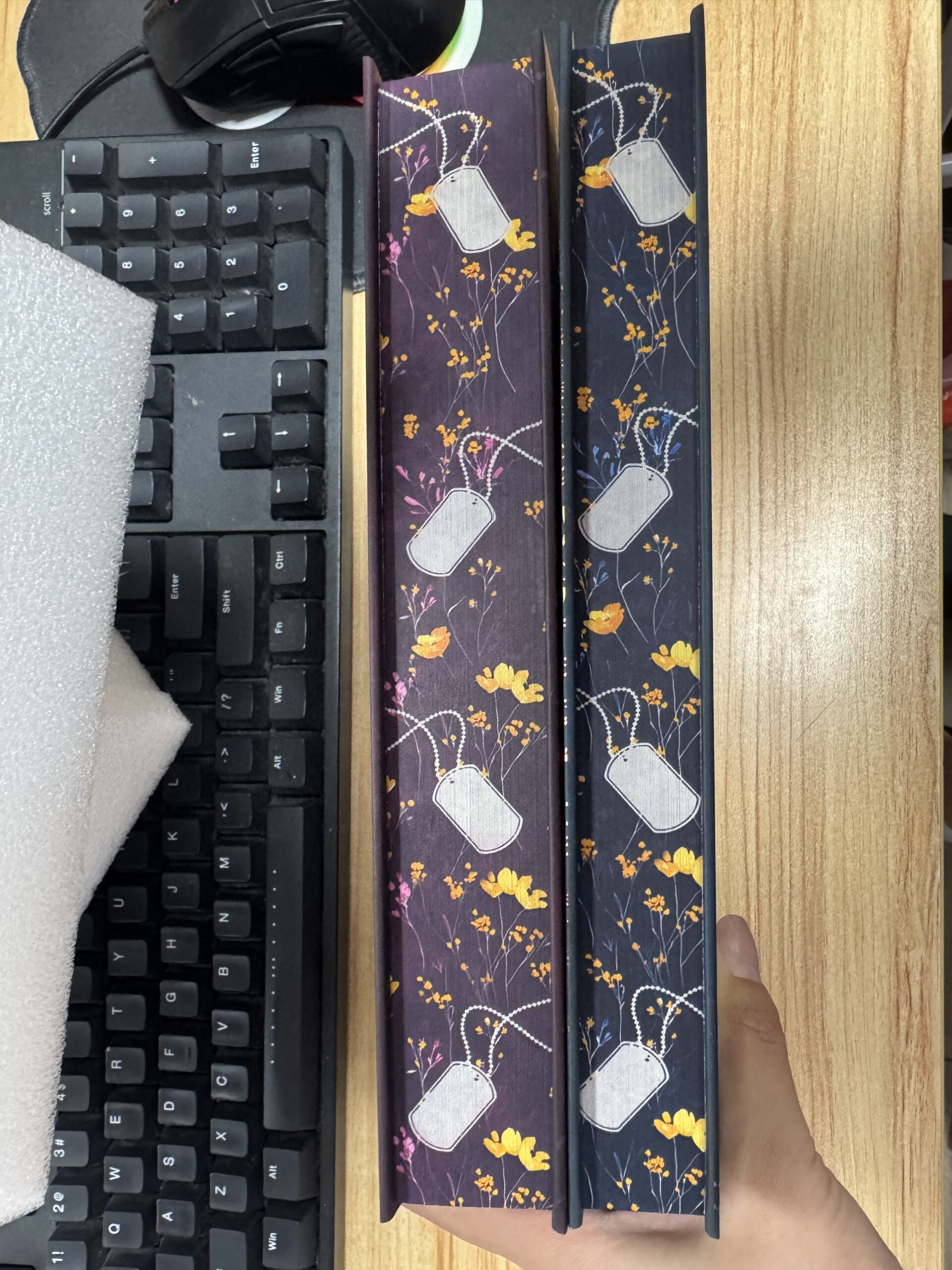hardcover copies of Welcome to the Fall and After the Fall special edition. deep mauve and deep blue covers with gold letters and dog tags among flowers. 